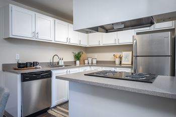 a kitchen with white cabinets and stainless steel appliances and a counter top at Sundial Apartments, Oregon, 97070